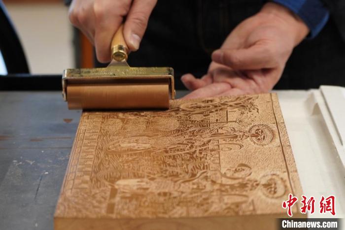 圖為徐晉林工作室工作人員正在給雕好壁畫的版面滾油墨?！【琶赖┰?　攝