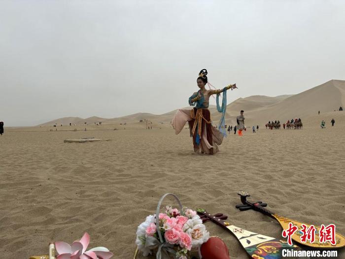 圖為2023年4月底，敦煌大漠“逐舞者”奧楠在鳴沙山月牙泉景區(qū)視頻直播敦煌舞?！●T志軍 攝