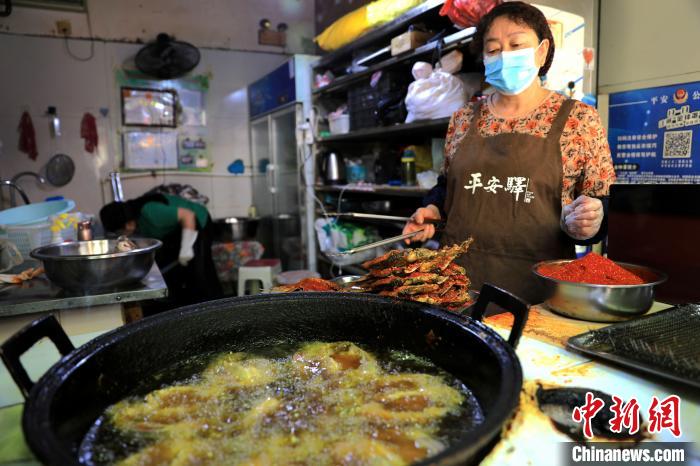 圖為平安驛·河湟民俗文化體驗地內(nèi)的商戶炸干板魚?！⊙Φ?攝